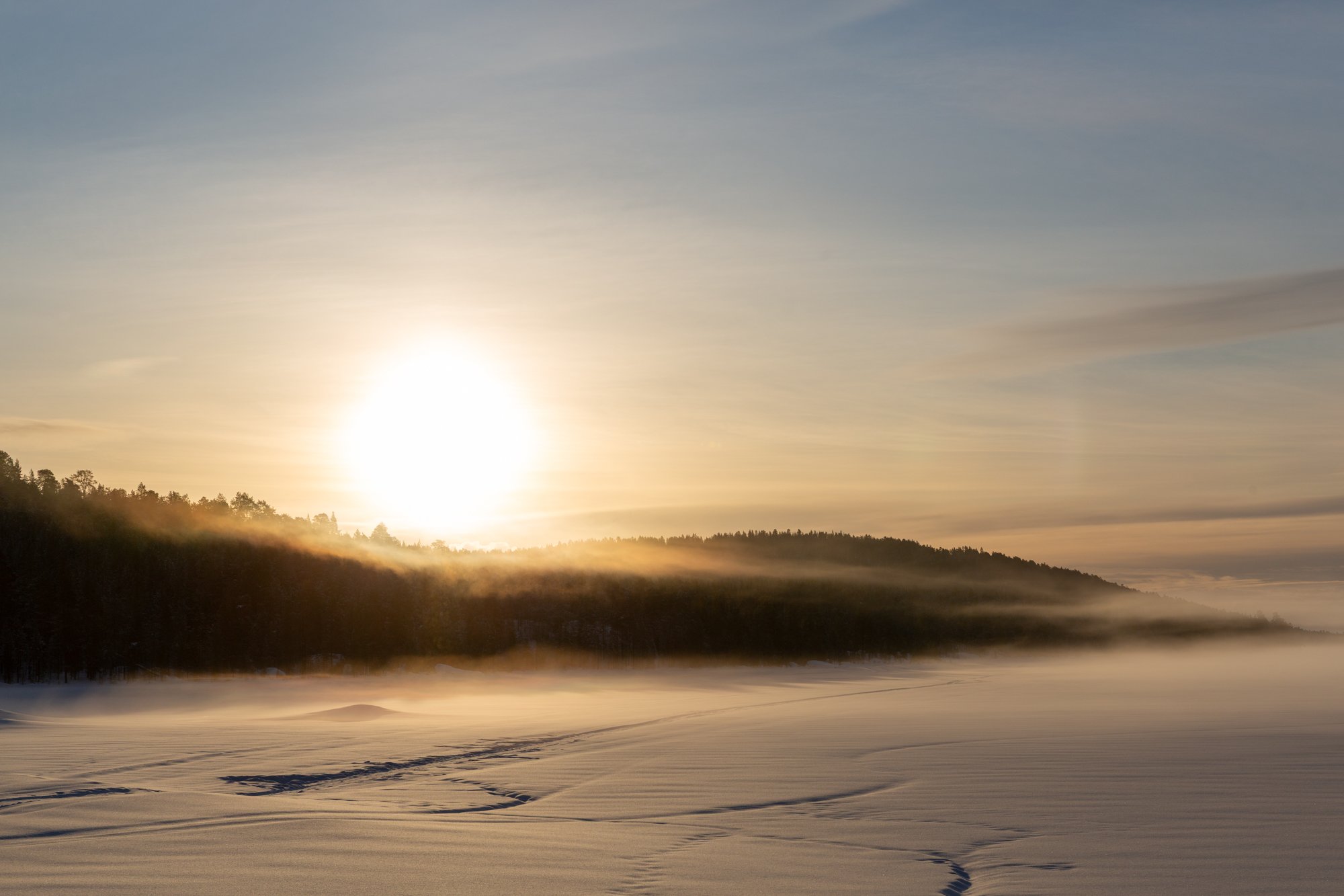 Auringon nousu järven yllä talvella.